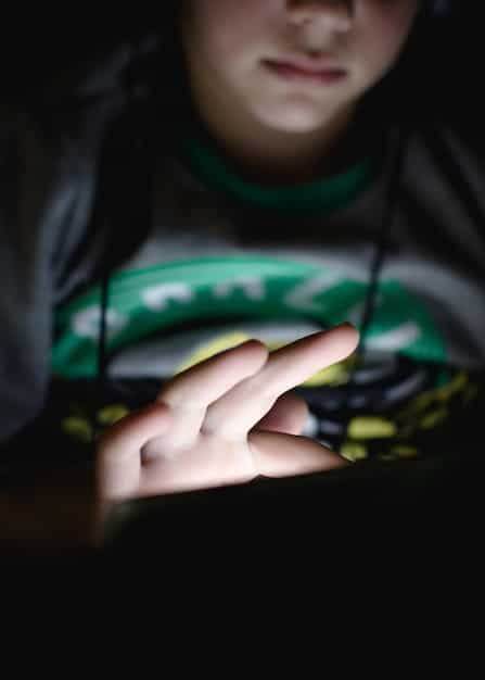 A close-up shot of a student esports player intensely focused on their gaming monitor, fingers poised over a mechanical keyboard, with a university esports jersey visible. The background is slightly blurred to emphasize the player.
