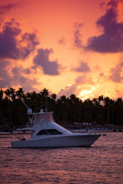 A heavily armed speedboat racing through a tropical canal, with a luxury yacht in the background and palm trees lining the shore. The sun is setting, casting a golden glow on the scene.