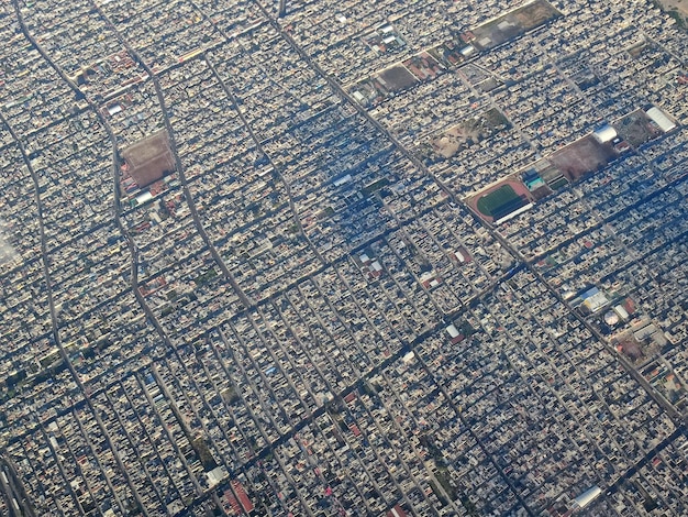 An aerial view of a sprawling, highly detailed fictional city with a complex network of roads, skyscrapers of varying heights, and distinct districts reflecting different architectural styles and cultural influences, showcasing the density and verticality of modern open-world game environments.