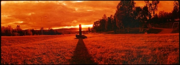 A panoramic view of a vast, open landscape in Red Dead Redemption 2, showcasing the game's impressive draw distance, detailed environmental textures, and realistic lighting effects during sunset.